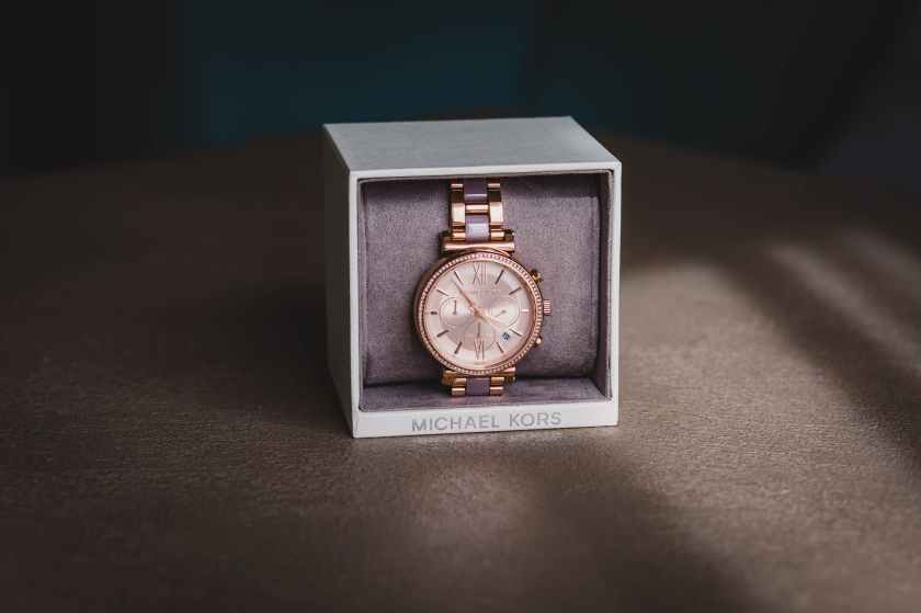 round gold colored analog watch with link bracelet and box